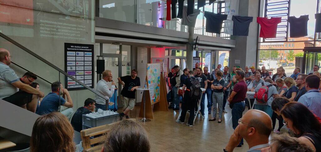 Eröffnung im großen Foyer des Wissenschaftszentrums. Eine Person steht auf der Treppe und sprich in ein Mikrofon. Alle anderen hören zu. 